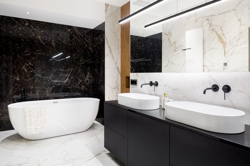 Salle de bains luxueuse avec carreaux de marbre foncé et lumineux et grande baignoire